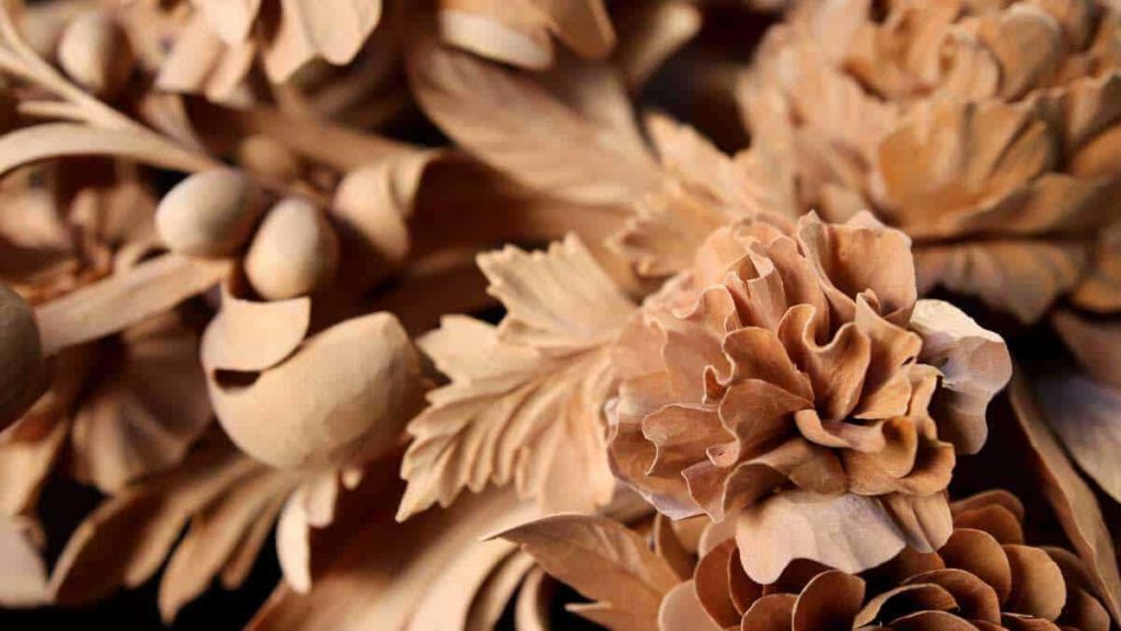 Alt text: Close-up of beautifully carved wooden flowers and leaves, showcasing detailed craftsmanship in wood carving. Perfect for those interested in wood carving classes and lessons.