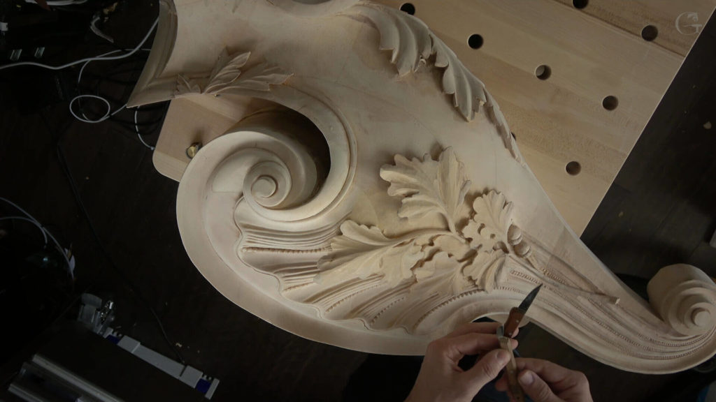 A close-up view of a skilled wood carver's hands working on an intricate design, showcasing beautiful details on a piece of carved wood. This image highlights the artistry involved in wood carving, perfect for those interested in wood carving classes and lessons.