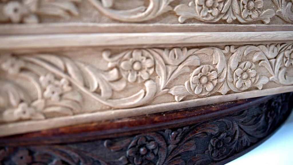 Alt text: Close-up of beautifully carved floral designs on a wooden panel, showcasing intricate details and craftsmanship, perfect for promoting wood carving classes and lessons.