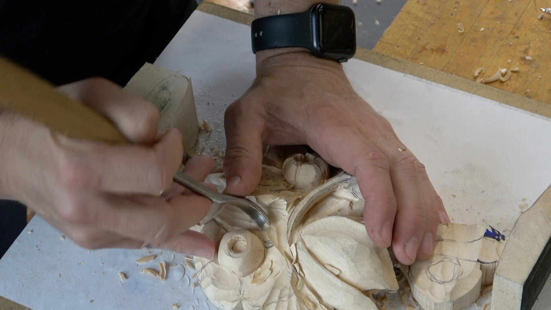 A close-up of hands carving wood, using a gouge tool to shape a detailed design. This image captures the craft of wood carving, showcasing the artistry involved in creating intricate patterns and features. Ideal for those interested in wood carving classes or lessons, it emphasizes the skill required in this fulfilling hobby.