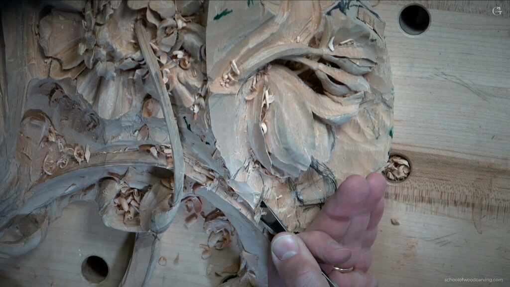 A person is carving a piece of wood with a chisel using the best wood carving tools they learned about in their beginners guide to wood carving.