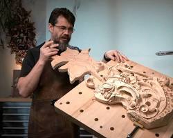 A person demonstrating wood carving techniques in a workshop, showcasing a detailed carved piece on a workbench. This image highlights the artistry involved in wood carving classes and lessons.