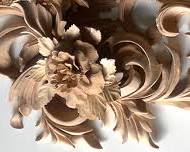 A detailed and intricate wood carving design featuring flowers and swirling patterns. This artwork showcases the beauty and skill involved in wood carving, perfect for those interested in wood carving classes and lessons.