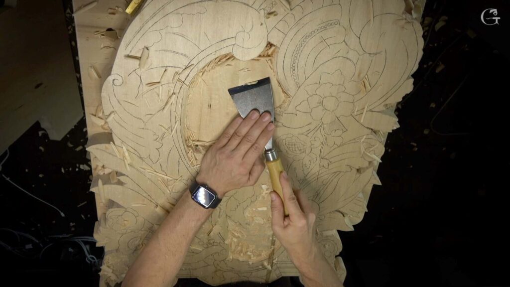 WOODCARVING LESSONS: Alexander Grabovetskiy is carving a detailed wood design with a chisel. This is great for beginners learning woodcarving online. You can see the person's hands, with a watch on the left wrist. The wooden piece shows floral and fancy patterns, similar to what you learn in top kids' woodcarving courses taught by Woodcarver Grabovetskiy. - Wood Carving tutorials

Alexander Grabovetskiy expertly carves wood for architectural design, focusing on how to create detailed elements from a block of basswood. He uses a variety of carving tools, including sharp wood carving knives and gouges of various sizes to achieve intricate shapes. Employing advanced techniques like chip carving, he shapes beautiful wood pieces that can be used as decorative elements in architecture. Alexander emphasizes the importance of selecting the right type of wood and shares tips for beginners on how to sharpen blades and choose suitable tools from their beavercraft kit. He combines spoon carving and whittling techniques to produce unique wooden figurines that can complement architectural features. The beautiful wood grain and texture enhance the charm of his designs. His unique wood carving style is evident as he creates sculptural objects—with the goal of integrating them into furniture and decorative decorations in buildings. On his YouTube channel, he provides step-by-step guidance on various types of wood carving for aspiring woodworkers looking to enhance their basic skills and create beautiful architectural components. This image highlights Alexander's inspiring work in woodworking, showcasing the best practices for carving wood in architectural design.