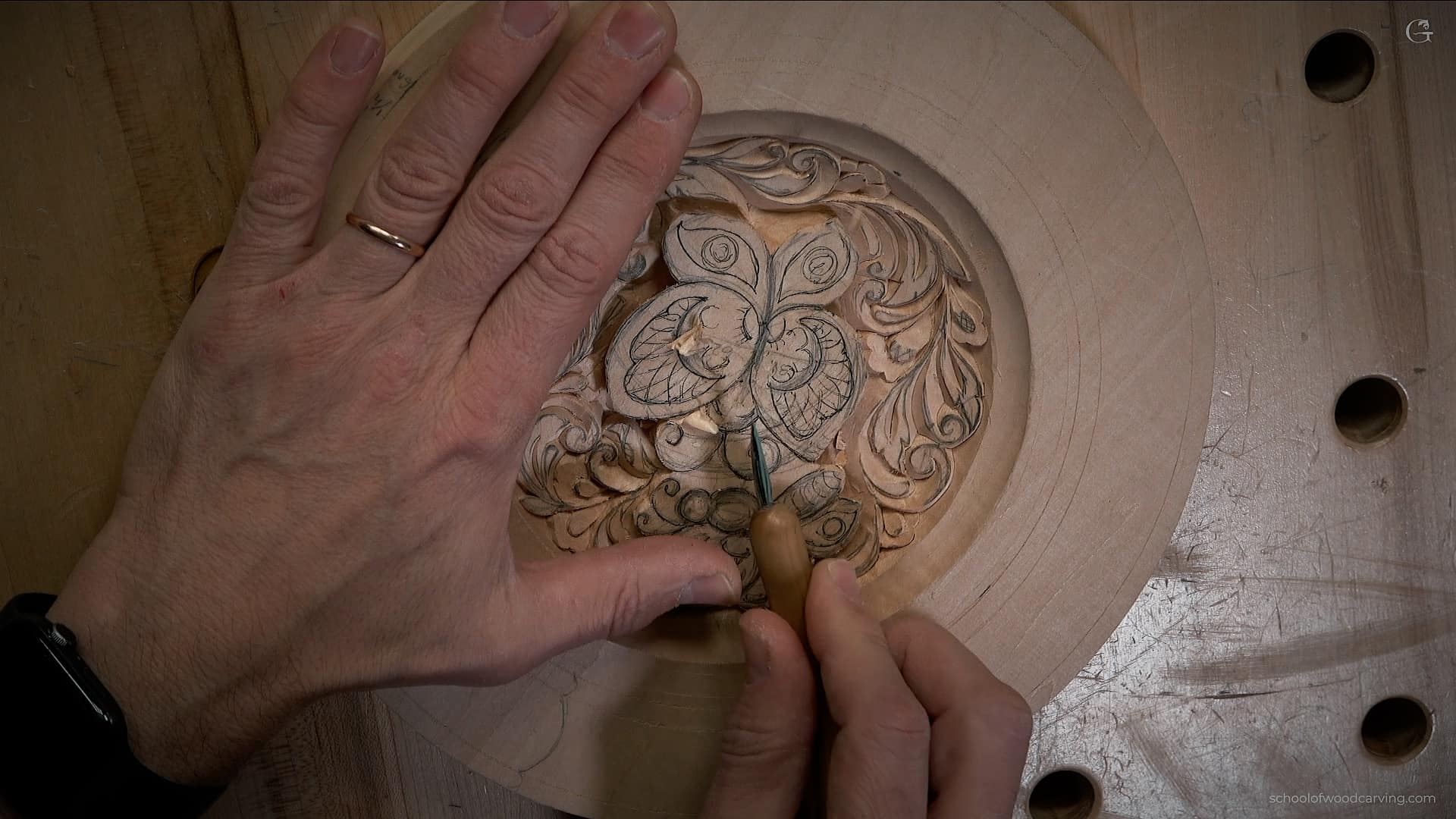 How long it take to learn woo carving A close-up view of a person's hands carving a detailed butterfly design into a wooden plate, showcasing intricate patterns. Learning this skill raises the question: how long does it take to learn how to carve wood?