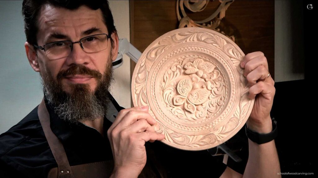 A person holding a beautifully carved wooden plate with floral designs. The individual looks proud of their work, which showcases their skills in wood carving. This image represents the essence of wood carving classes and lessons, inviting others to explore this art form.