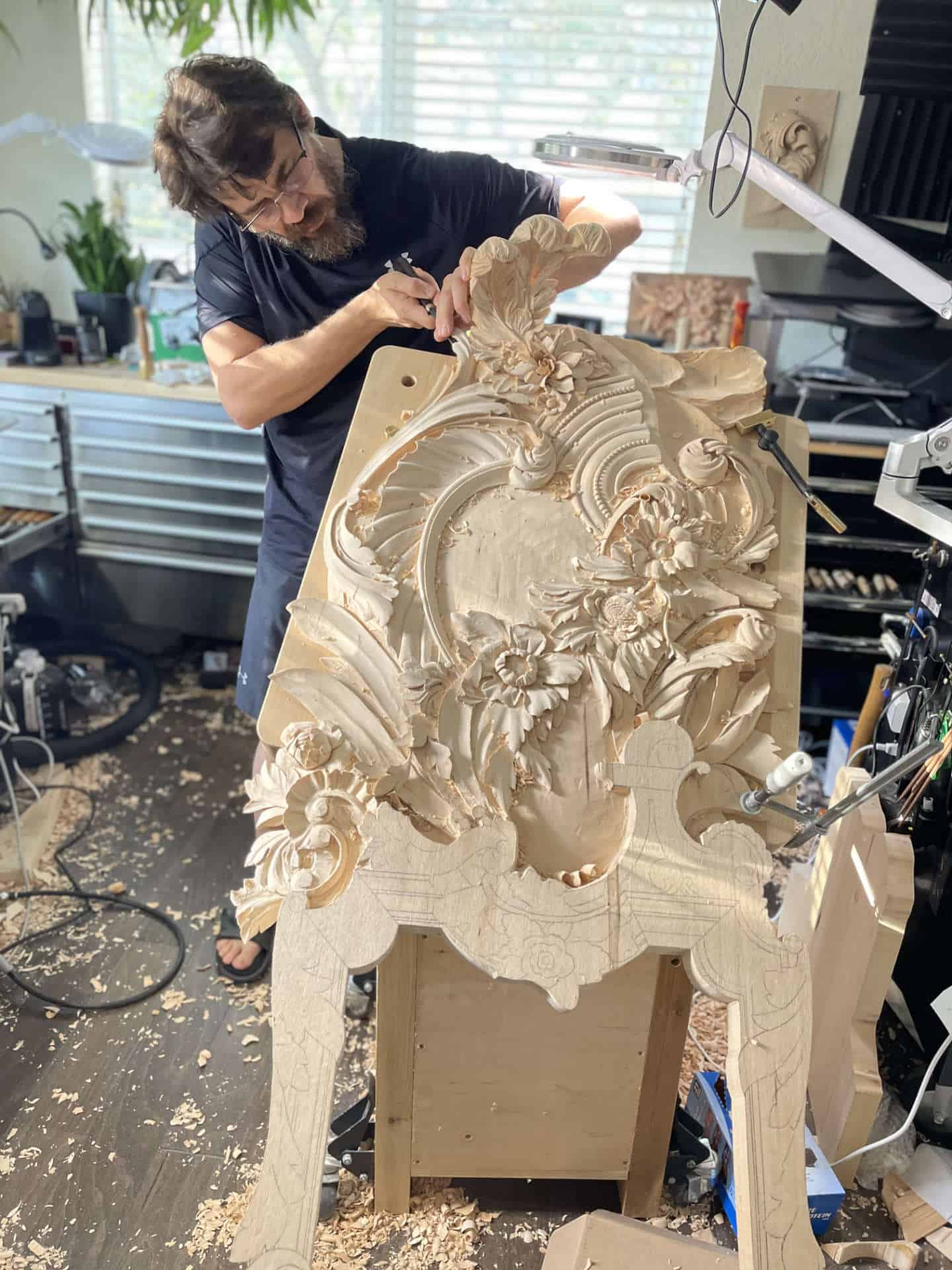 Potential to Make Money from Carving Wood Alexander Grabovetskiy is skillfully carving a large panel in Venetian style, showcasing the art of wood carving. This scene captures the intricate process of carving wood as he works with a sharp chisel and various tools, embodying the skill of a woodworker. His dedication to creating an object of beauty is evident as he transforms a simple piece of wood into a stunning work of art. This woodcarver is not only passionate about his craft but is also focused on making money carving wood. The image illustrates the potential for a profitable woodworking business, where his artwork can be sold at local craft fairs or through online marketplaces like Etsy. With the right tools and techniques, he demonstrates how woodworking can be both an art form and a profitable business venture. As he expertly engages in chip carving and relief carving, it&rsquo;s clear that he has invested time in mastering his craft. The tools displayed around him highlight the importance of using the right tools for successful wood carving projects. This image serves as inspiration for aspiring woodworkers looking to turn their hobby into a profitable business, emphasizing that with skill and dedication, one can make enough money selling wood carvings while creating beautiful pieces of art.