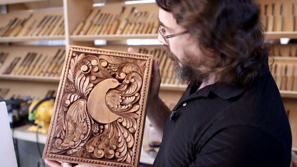 Finished curly cutting board with a stylized bird of paradise carved across its face