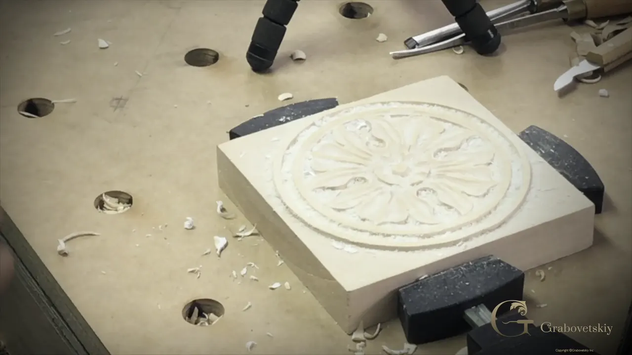 Carved basswood rosette clamped on the bench, eight petals around a button, shavings all around it.