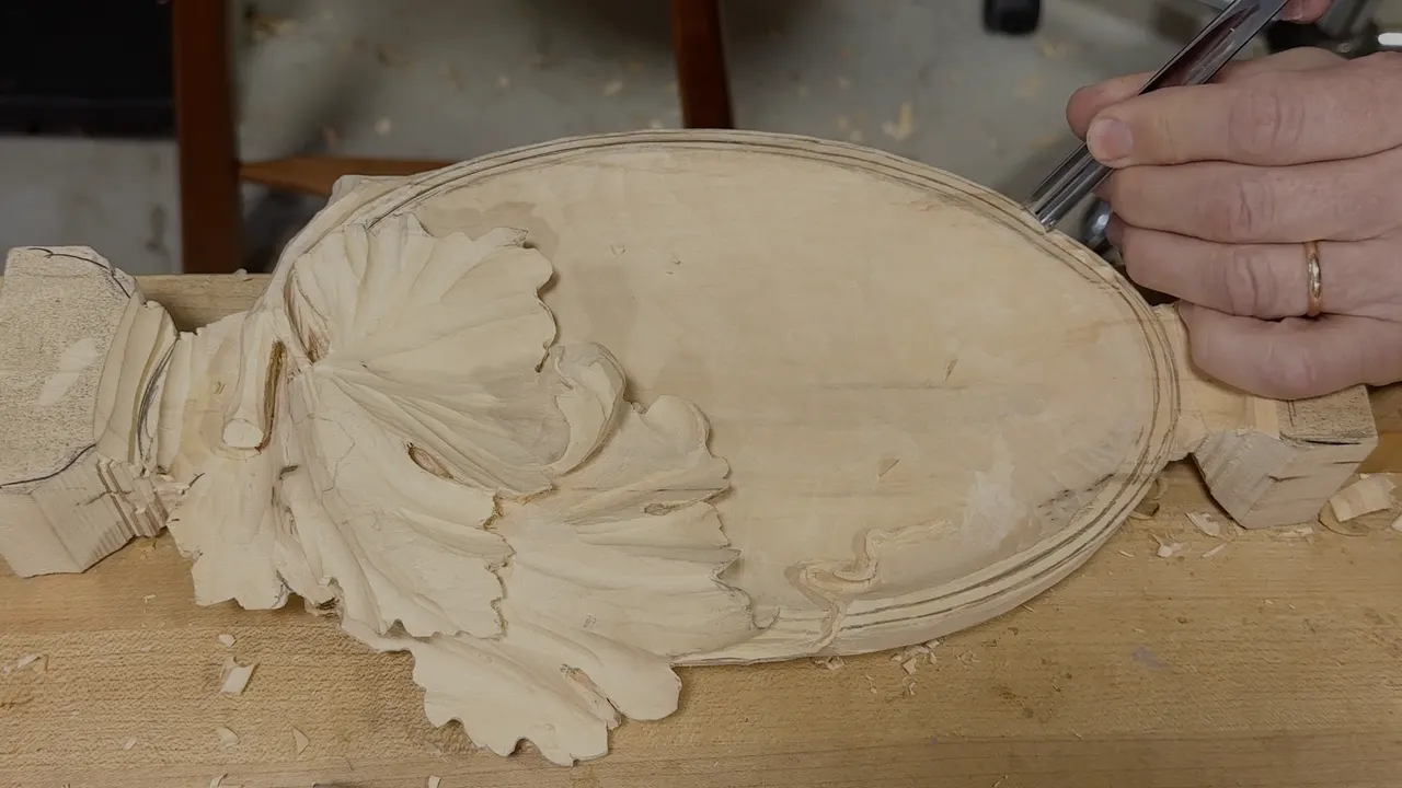 Carved basswood tray from above, the grape leaf filling one end and a fine line cut around the rim.
