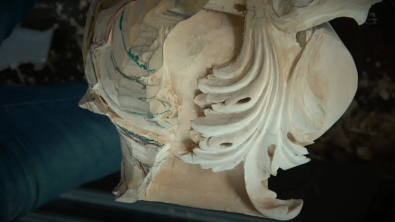 Carved acanthus lobes with round holes beside a rough side still covered in pencil and colored lines