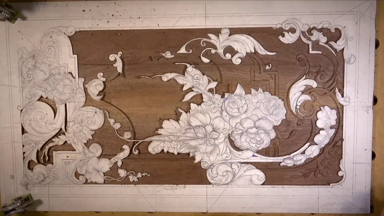 The whole walnut panel seen straight down from above, paper patterns still glued on the flowers and scrolls