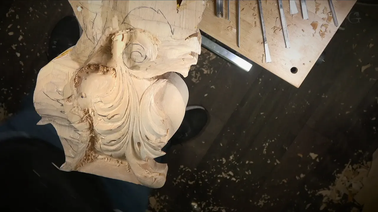 Top view of the carved acanthus leaf, its pipe and scrolls, with gouges laid out on a board