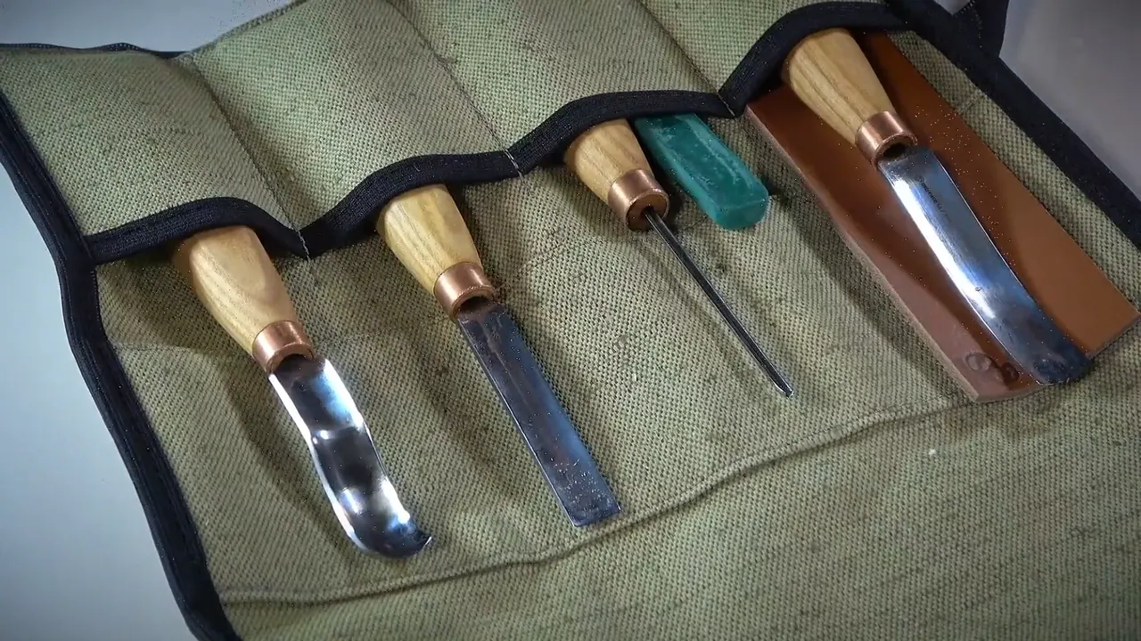 Five BeaverCraft tools laid in the canvas roll that comes with the set.