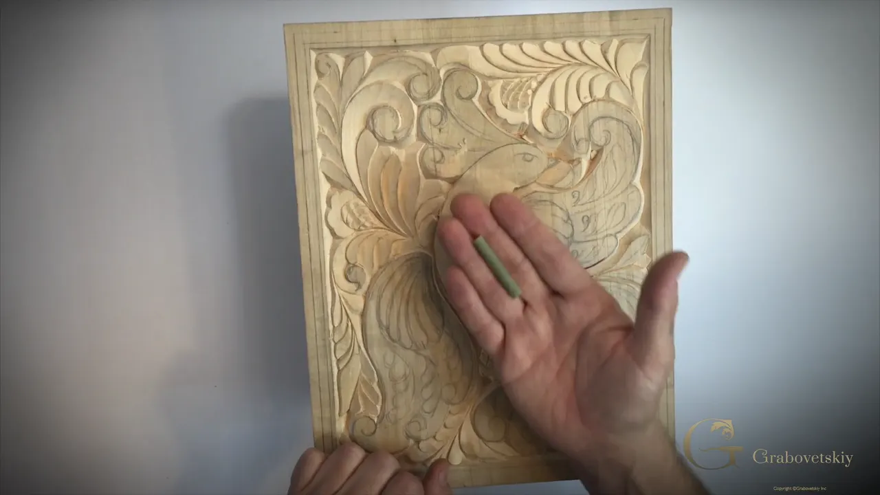 A cut length of Dutch rush lying in an open palm above a carved basswood panel.