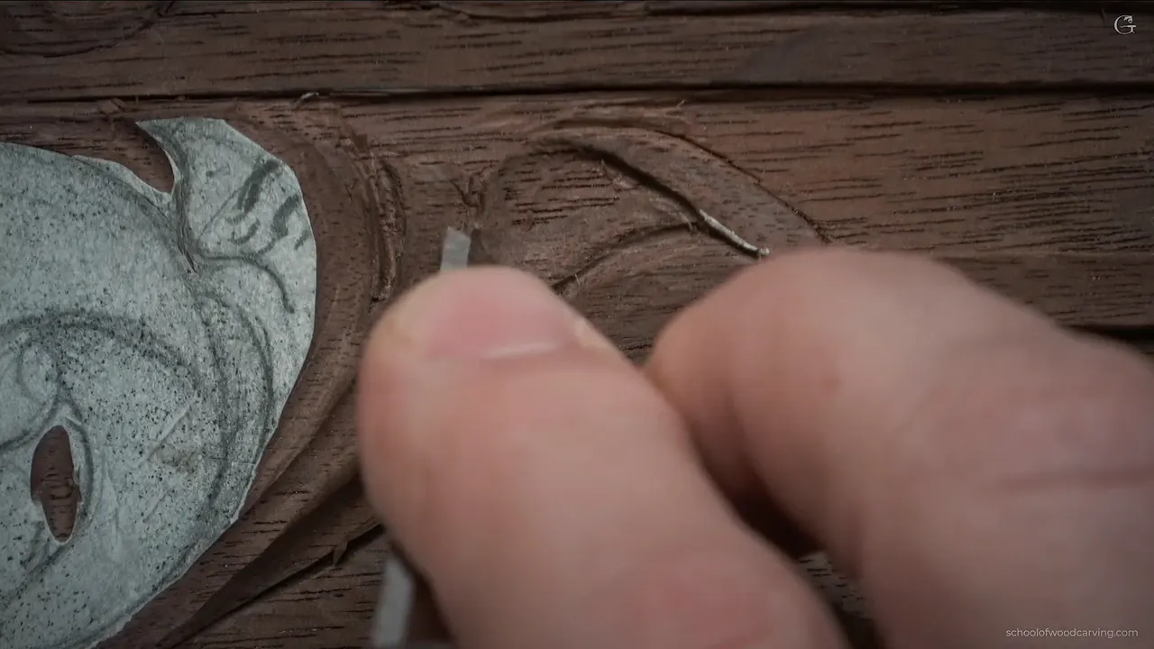 Two fingers pinch a thin blade beside the scroll, its paper pattern still on