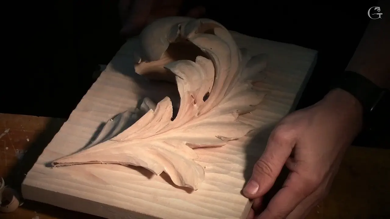 The finished panel held at both edges in warm light, the pierced leaf standing off its board