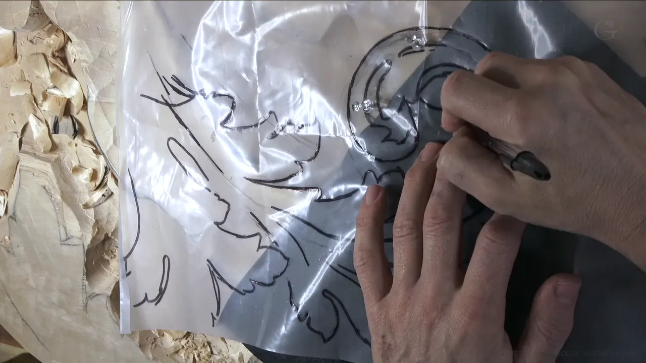 A ball pen traces the plastic drawing while gray carbon paper shows through underneath.