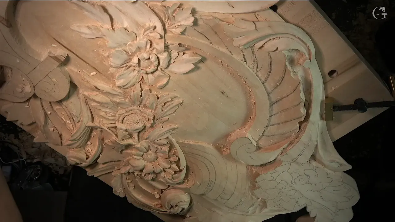 Seen from above, the panel shows carved flowers, a scroll and a curved band still drawn in pencil