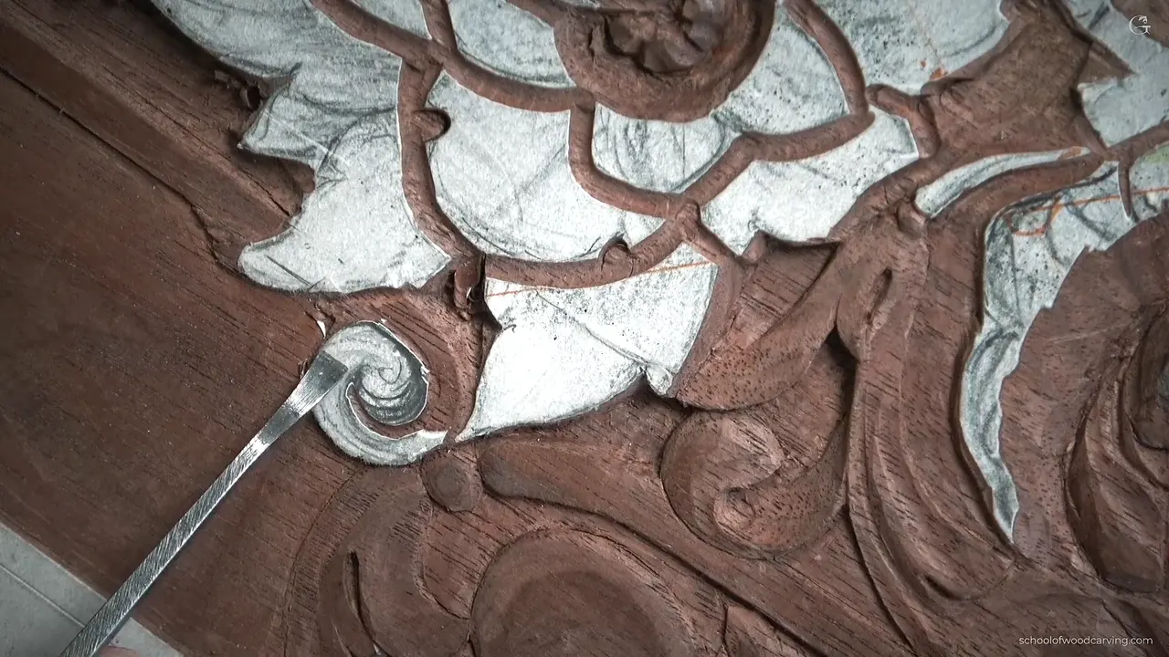 Thin steel tool pointing at the small volute, still under its paper pattern