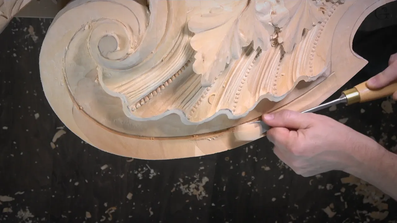 A wide gouge runs along the groove at the outer edge, below the shell and the scroll.