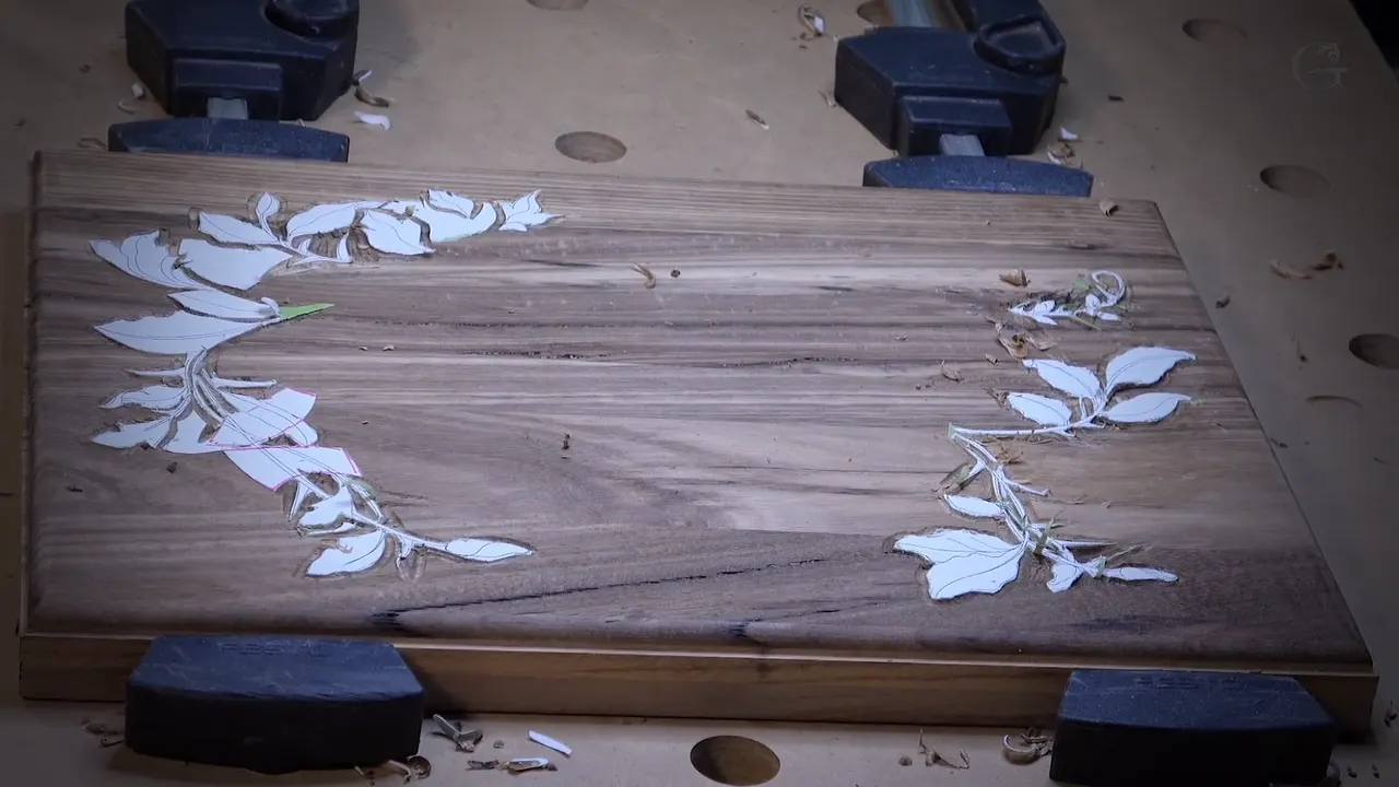 Acacia Bible box lid clamped to the bench, the first layer set in around paper leaves at both ends