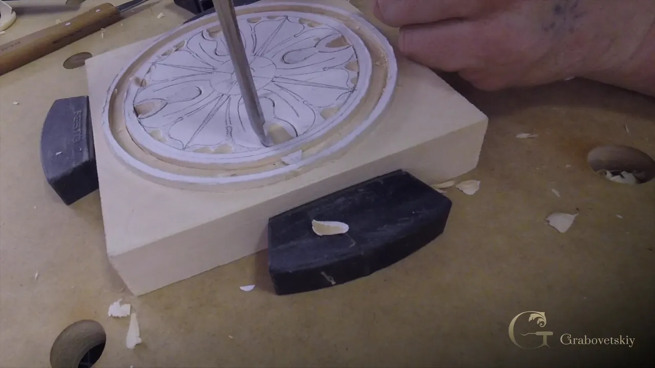 A gouge stands upright in one petal of the rosette, the block held by two clamps