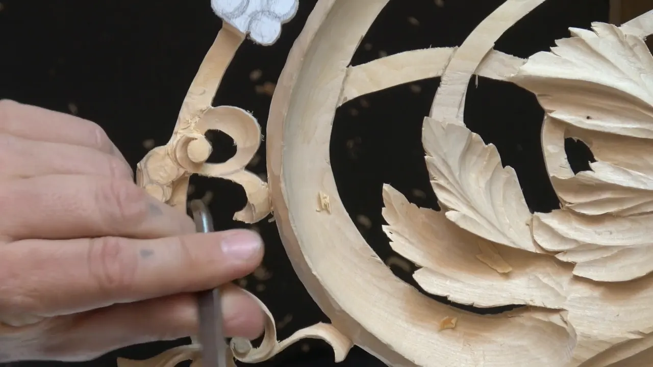 The outer scroll of the panel, where the curl and the acanthus meet and the fibres stop running the same way.