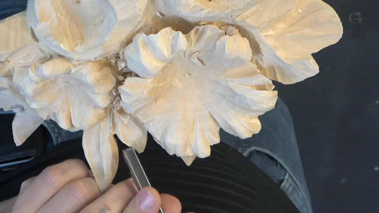 A gouge working under the rim of a leaf so it reads as growing out from beneath the flower.