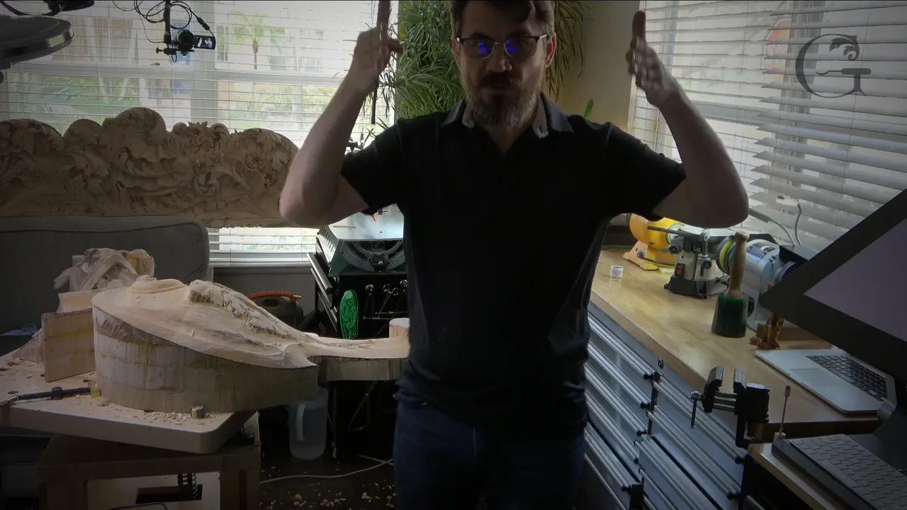Alexander Grabovetskiy standing in the studio with both hands raised, daylight through the window blinds behind him
