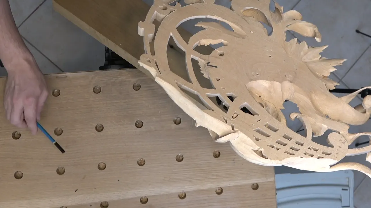 The pierced panel lying face up on the dog holed workbench, a small gouge in my hand beside it.