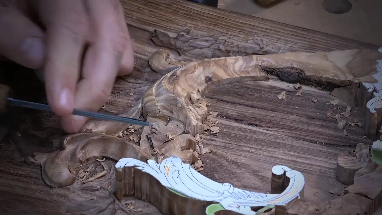 Veiner laid almost flat, its tip slipping under the olive wood scroll above a paper pattern piece