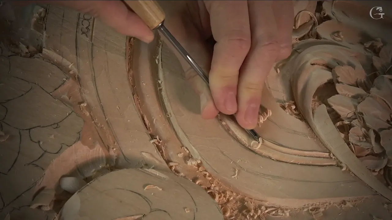 A small gouge pushed along a curved groove, chips lying on the band
