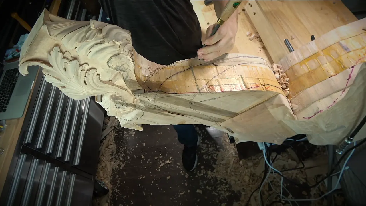 The corbel lying on its side, carved acanthus at one end and paper printouts along its length