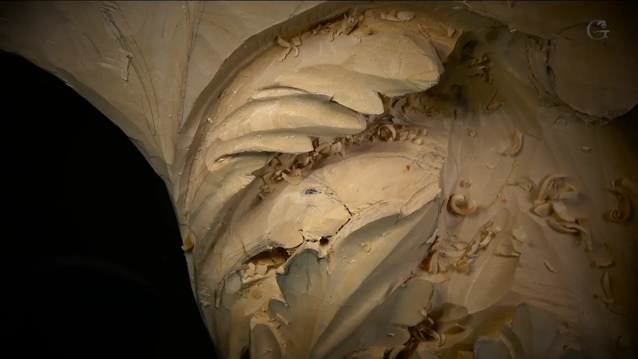 A thin lobe marked with black lines, a small dark hole carved just below them.