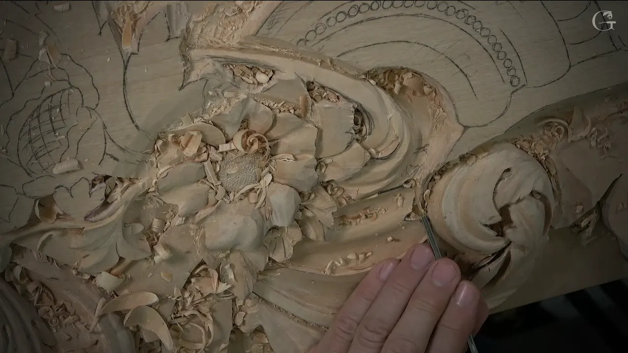 Tool held upright at the curl of the carved scroll, with fingers below steadying the steel