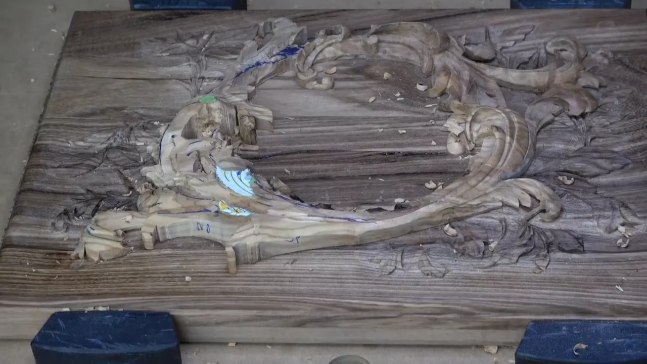 The whole lid on the bench, a pale olive layer curving over carved acacia, blue blocks at each corner