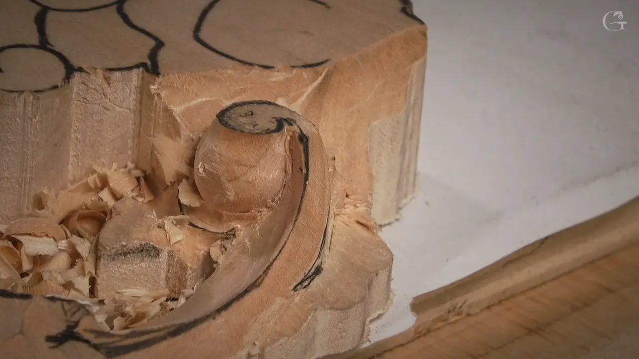 Volute carved into its roll, the spiral turning out of the block with shavings still lying around it