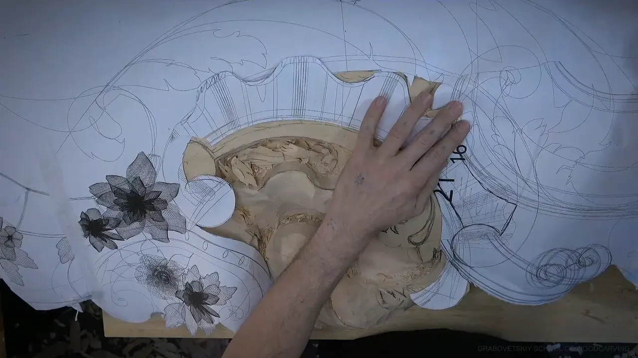 A hand presses the paper pattern flat over the half carved shell