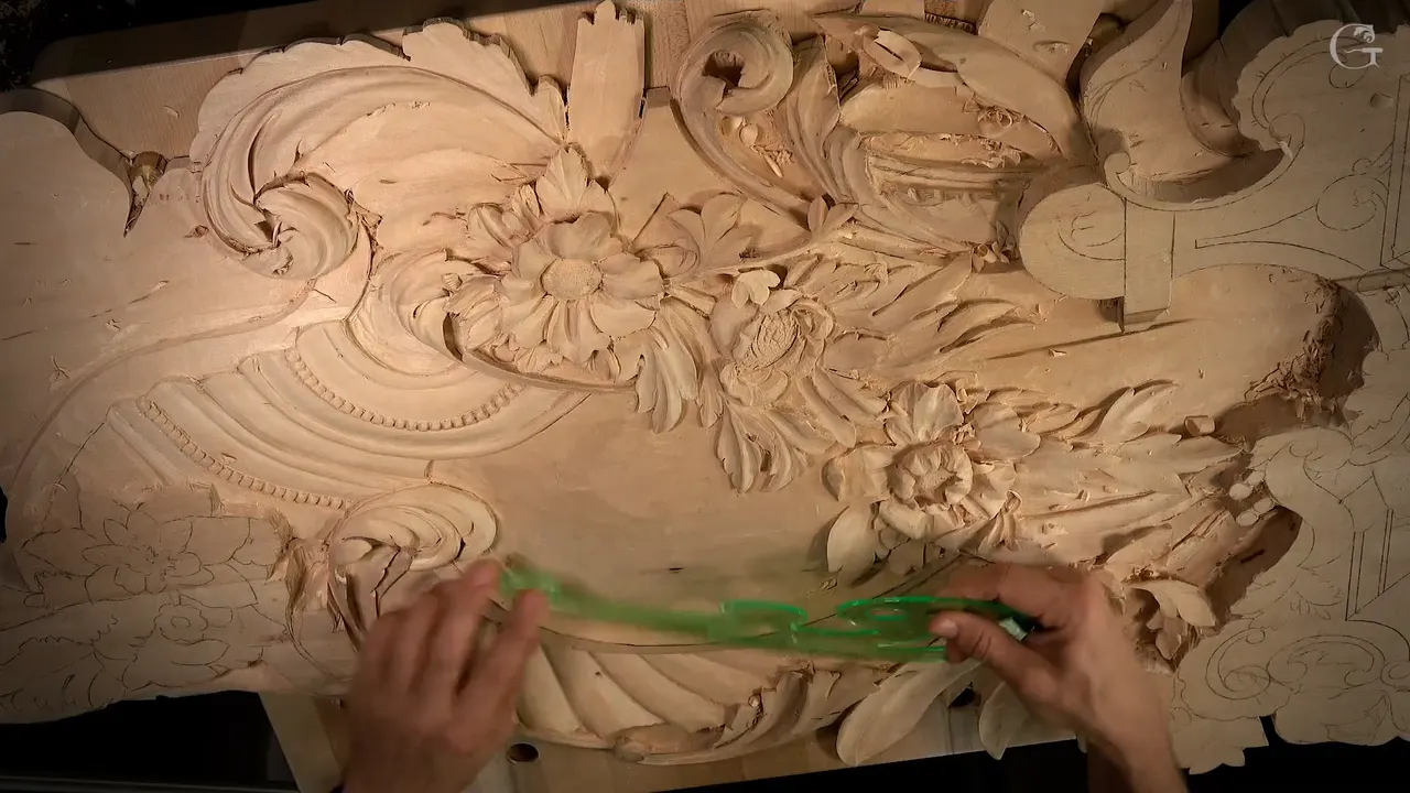 Both hands hold a green French curve to the pencil line of the carved arch