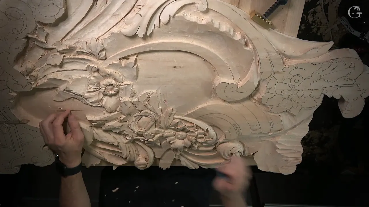 The carved panel from above, finished flowers and scrolls at left, pencil drawings of more flowers still waiting at right