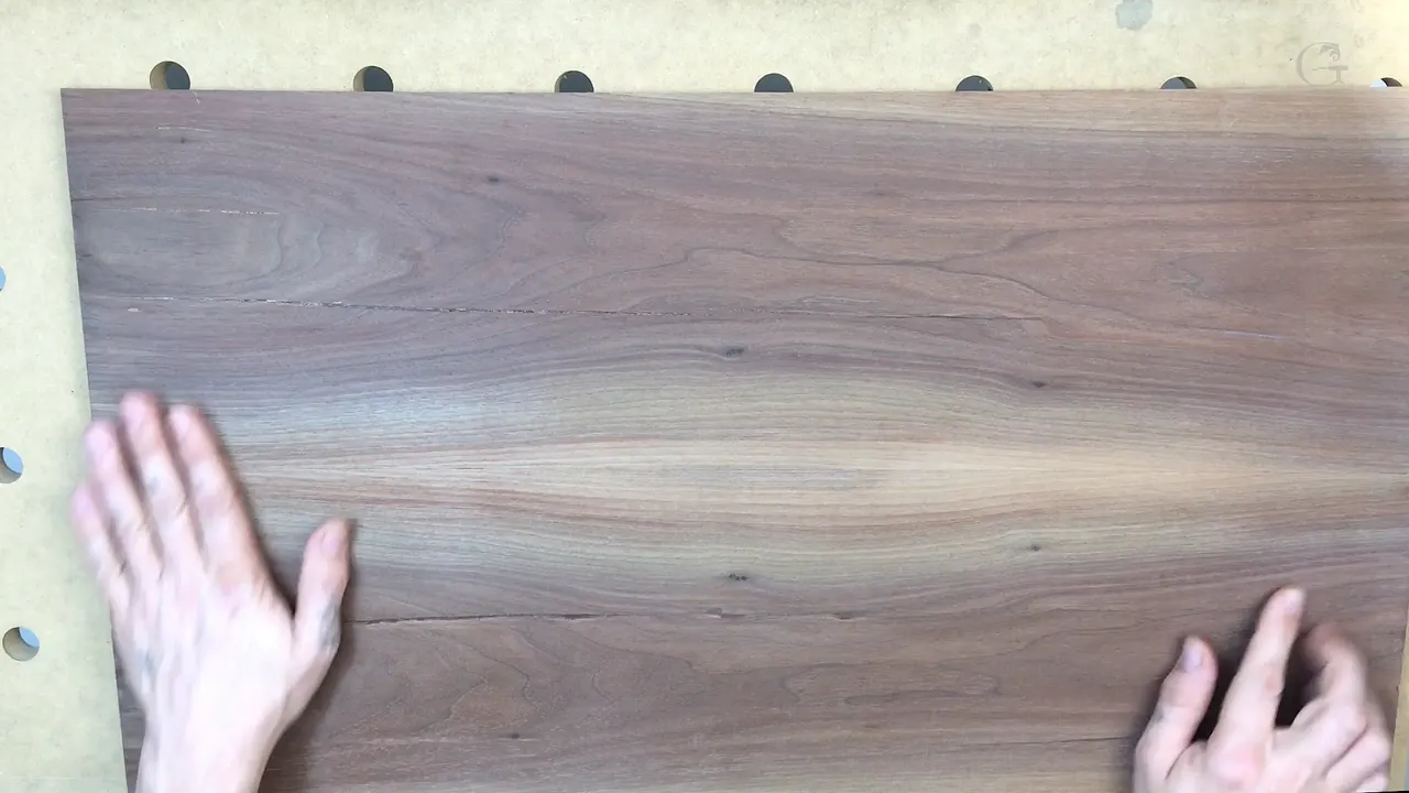 Walnut furniture panel lying face up on the bench board with both hands flat on it