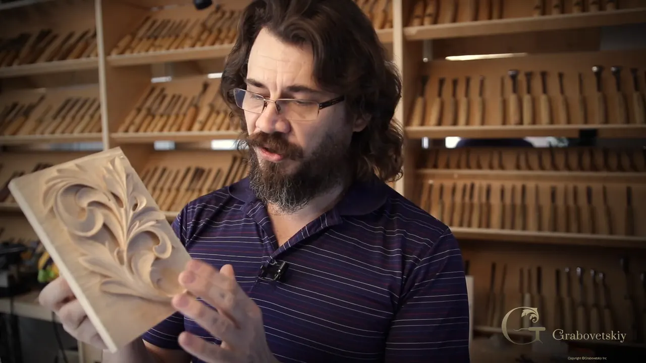 Alexander holds the carved Greek acanthus panel in front of his wall of gouges