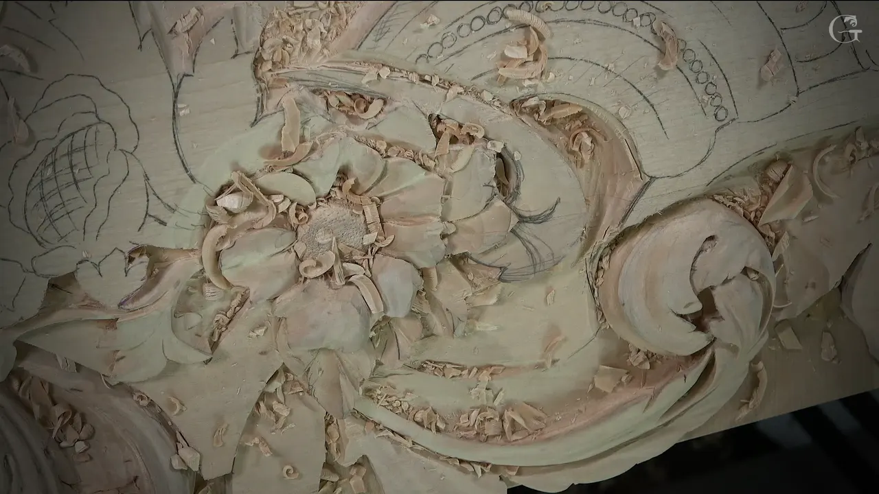 Carved flower with a punched center beside a rolled scroll, chips lying all over the board