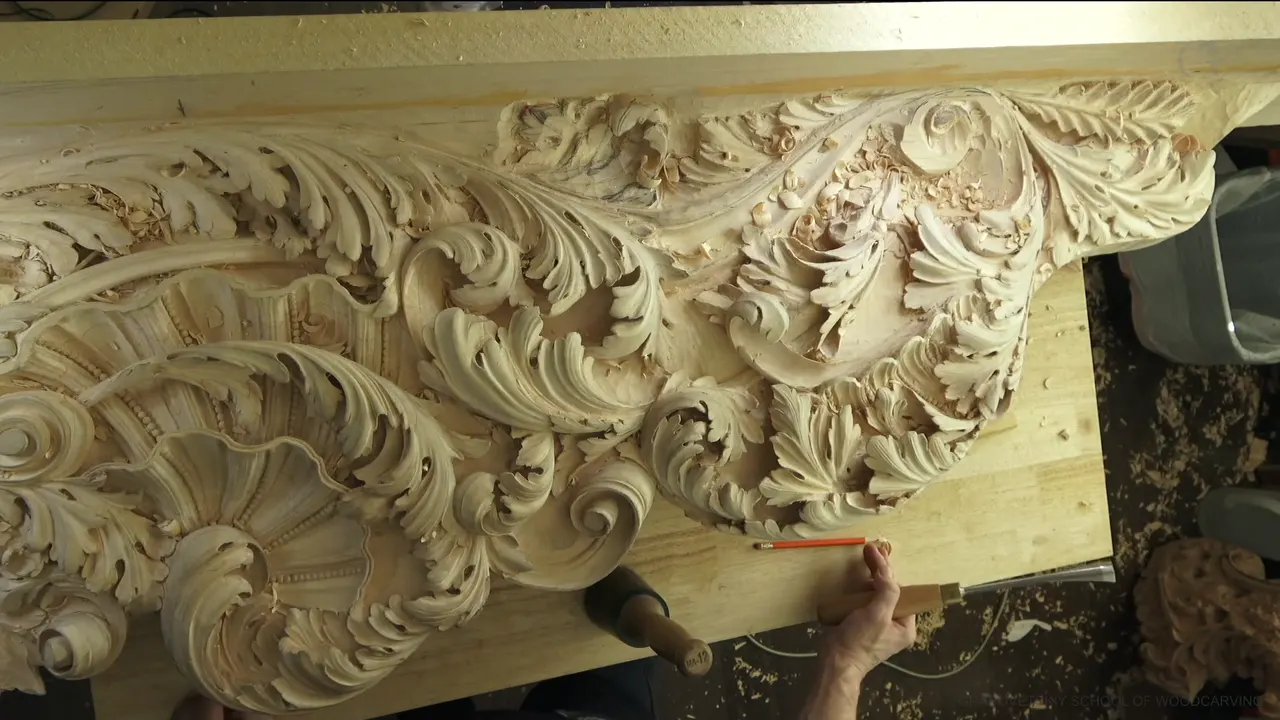 Top view of the full board with shell, scrolls and leaves, a red pencil held at the lower right.
