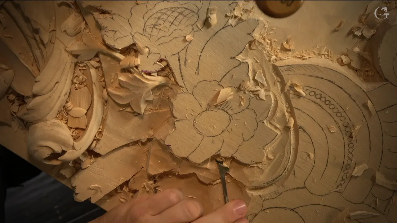 Drawn flower beside carved leaves and a scroll, a slim gouge resting at the lower edge.