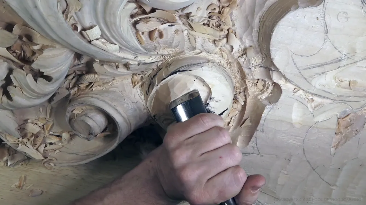 A big steel-ferruled gouge held in one fist, cutting into the rounded head of the leaf.