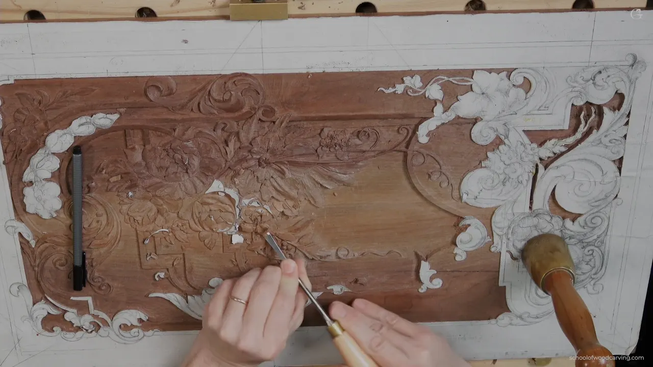 The whole carved panel from above, gouges laid across it, two flowers side by side.