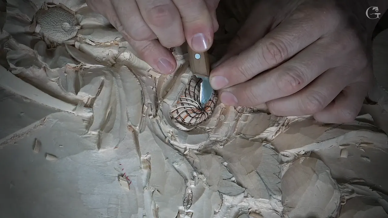A small knife blade sits in the orange and black lines at the middle of a carved flower