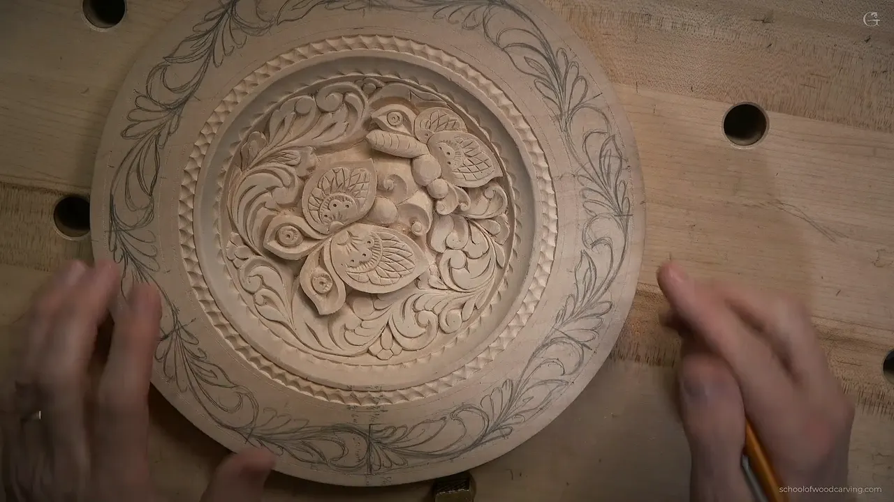 Overhead, a carved basswood plate with two butterflies in the middle and a pencil border drawn around its rim